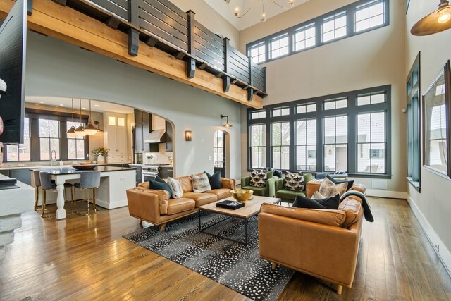 living room featuring arched walkways, hardwood / wood-style floors, a high ceiling, and baseboards