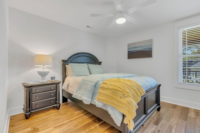bedroom with a ceiling fan, light wood-type flooring, visible vents, and baseboards