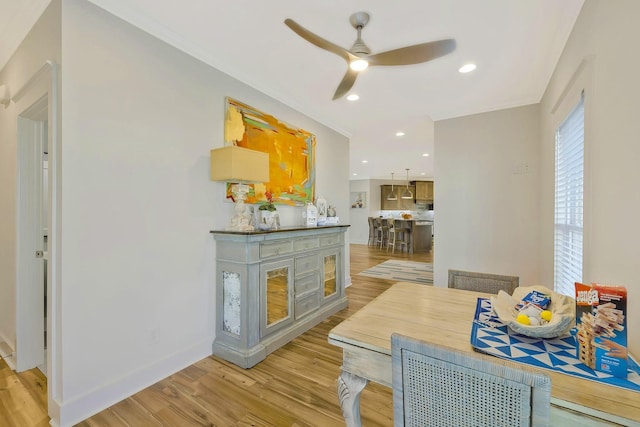 dining space with crown molding, visible vents, light wood-style floors, ceiling fan, and baseboards