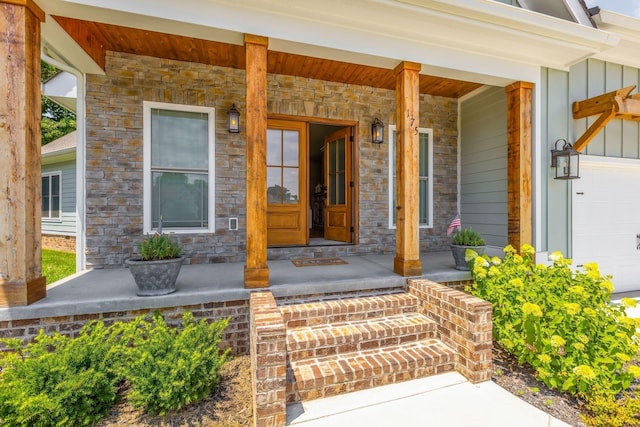 property entrance with a porch, stone siding, an attached garage, and board and batten siding