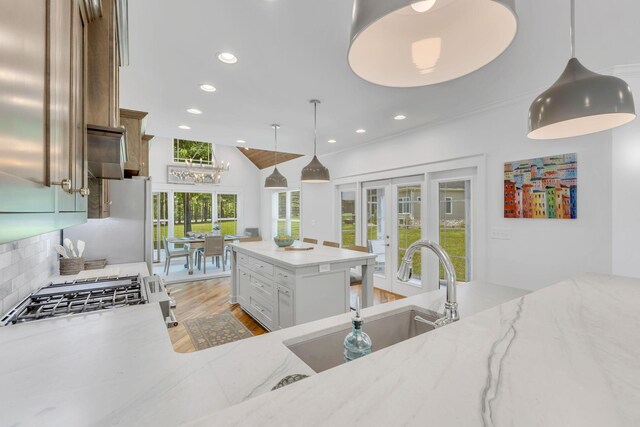 kitchen with light stone counters, french doors, light wood finished floors, backsplash, and a sink