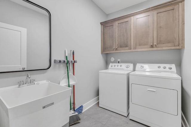 clothes washing area featuring cabinet space, a sink, washer and clothes dryer, and baseboards