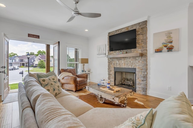 living room featuring baseboards, ornamental molding, wood finished floors, a fireplace, and recessed lighting