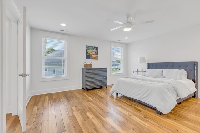 bedroom featuring light wood finished floors, baseboards, multiple windows, and visible vents