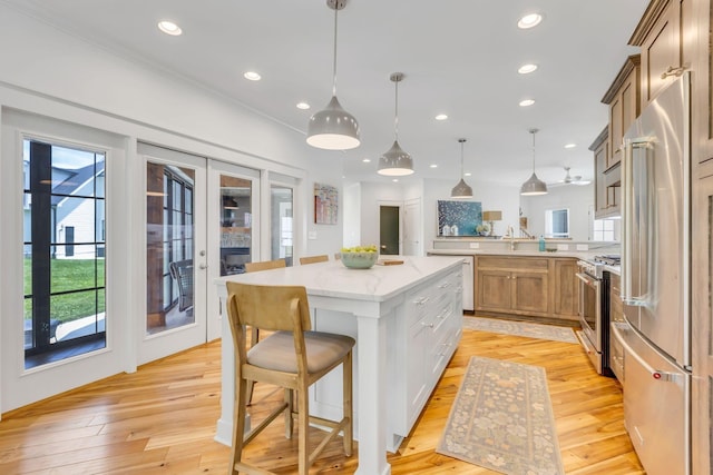 kitchen with light wood-style flooring, recessed lighting, a peninsula, light stone countertops, and high end appliances