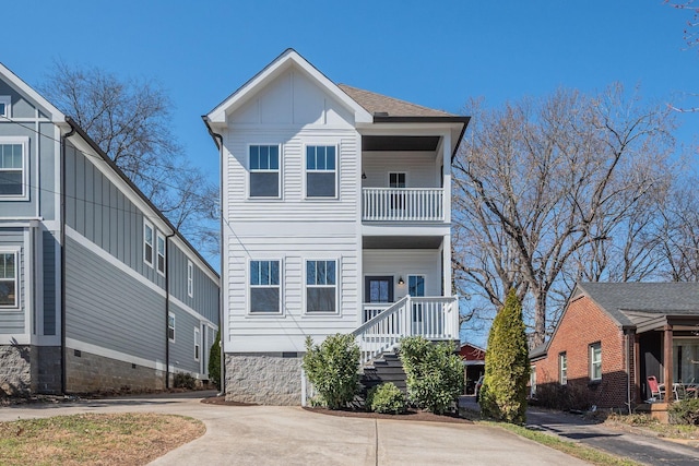 view of front of home featuring driveway, a shingled roof, board and batten siding, and a balcony