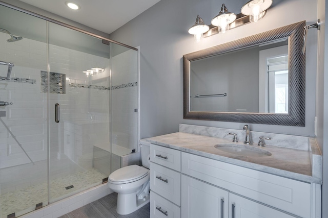 bathroom with a shower stall, toilet, and vanity