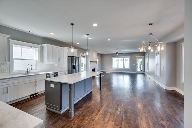 kitchen featuring dark wood-style flooring, a kitchen island, a sink, appliances with stainless steel finishes, and decorative backsplash