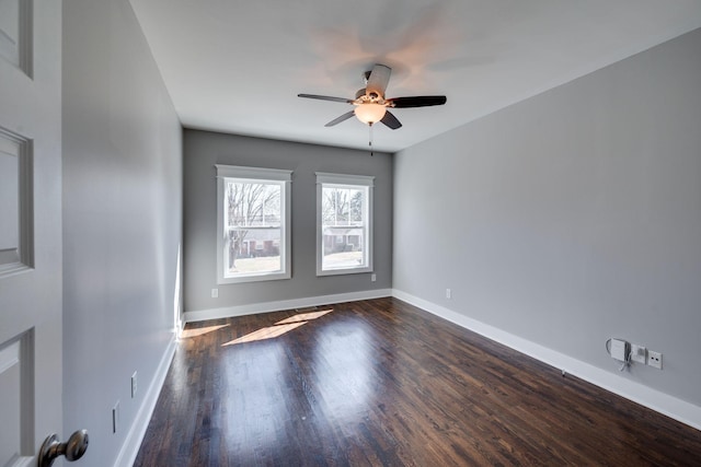 empty room with a ceiling fan, baseboards, and dark wood-type flooring