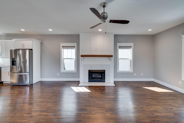 unfurnished living room with dark wood-style floors, recessed lighting, a fireplace, and baseboards