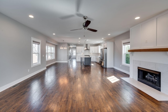 unfurnished living room with recessed lighting, dark wood-style flooring, and ceiling fan with notable chandelier