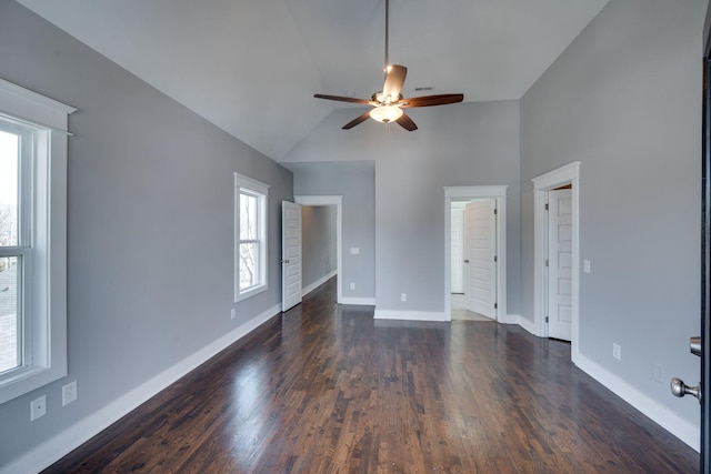 empty room with high vaulted ceiling, dark wood-style floors, baseboards, and a ceiling fan