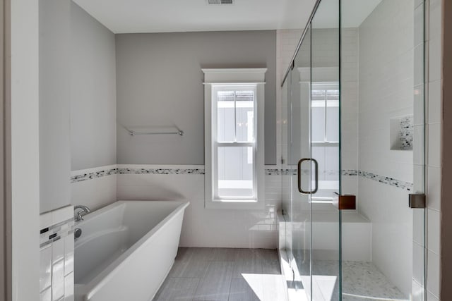 bathroom featuring a bath, visible vents, a stall shower, and tile walls