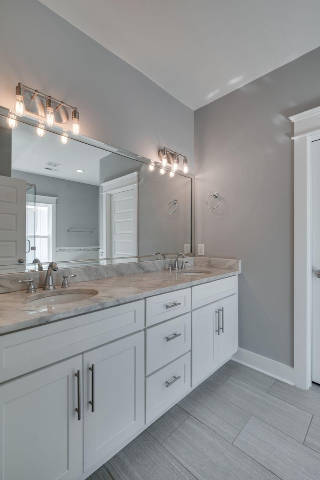 bathroom with double vanity, baseboards, and a sink