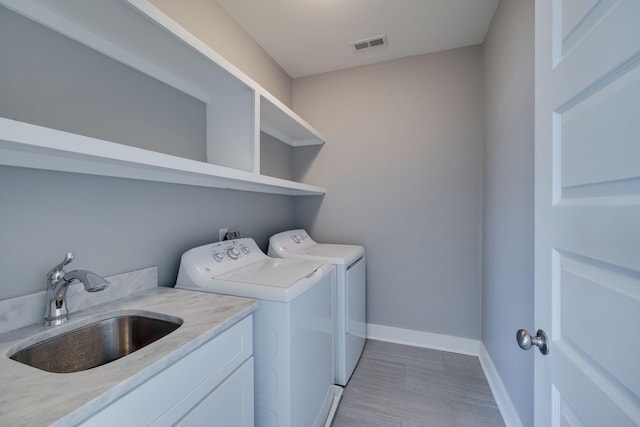 laundry area featuring a sink, washing machine and dryer, visible vents, and baseboards