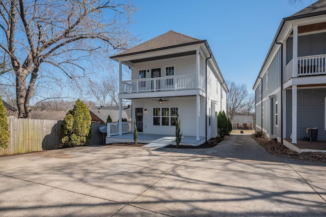 view of front of house featuring driveway, a ceiling fan, roof with shingles, fence, and a porch