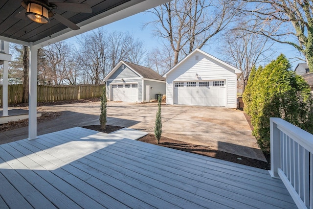 deck with a garage, ceiling fan, fence, and an outdoor structure