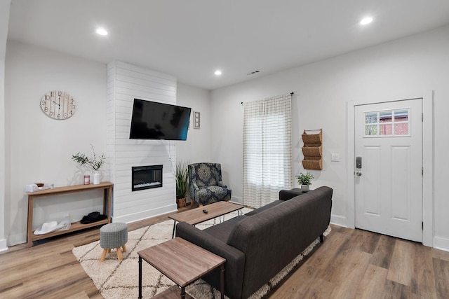 living room with a fireplace, wood finished floors, visible vents, and recessed lighting