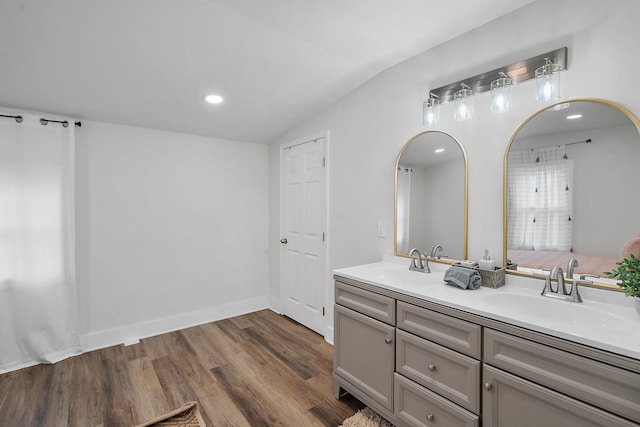 bathroom featuring vaulted ceiling, double vanity, a sink, and wood finished floors