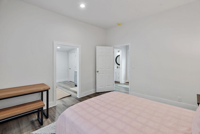 bedroom with baseboards, ensuite bathroom, dark wood-type flooring, and recessed lighting