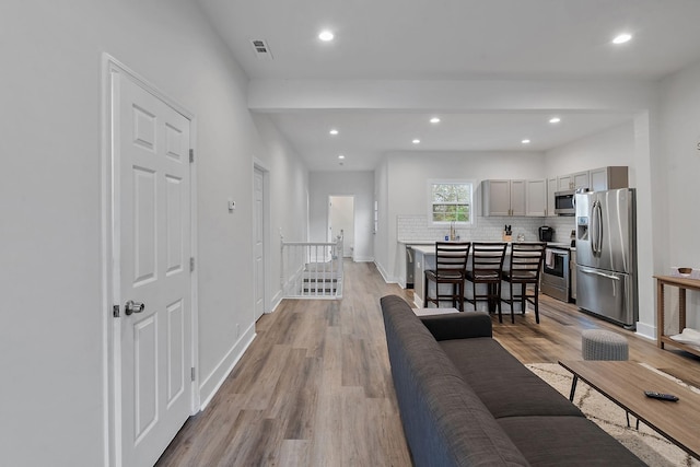 living area featuring baseboards, recessed lighting, and light wood-style floors