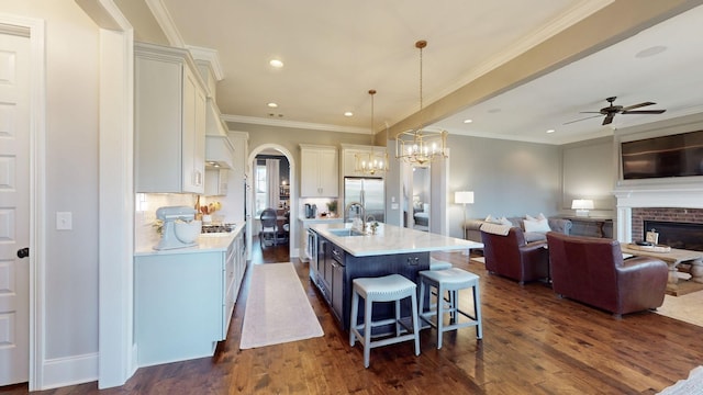 kitchen featuring light countertops, arched walkways, stainless steel fridge, and dark wood-style floors