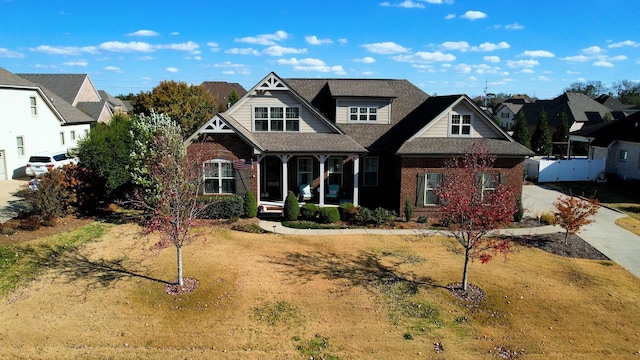 view of front of house featuring covered porch, a front yard, and brick siding