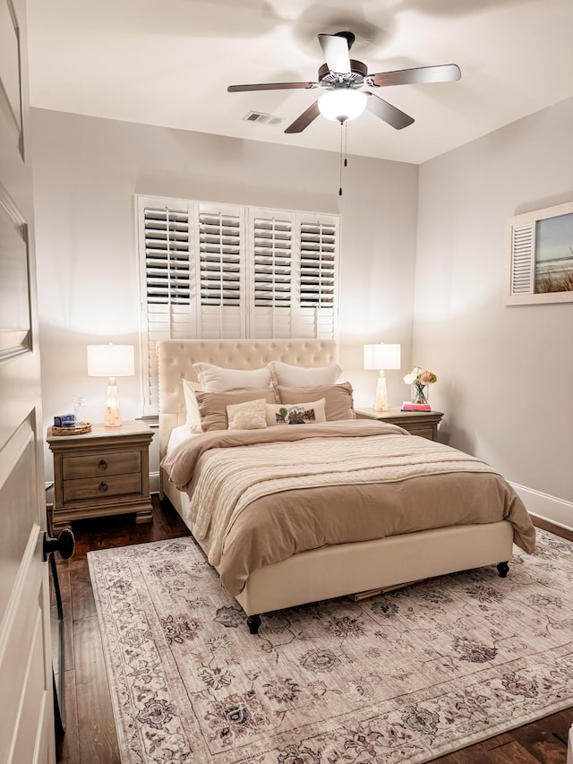 bedroom with dark wood-style floors, baseboards, visible vents, and a ceiling fan