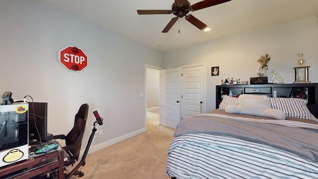 bedroom with light carpet, ceiling fan, a closet, and baseboards