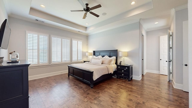 bedroom featuring a tray ceiling, dark wood-style flooring, visible vents, and baseboards