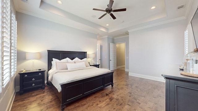 bedroom featuring a tray ceiling, crown molding, visible vents, dark wood-type flooring, and baseboards