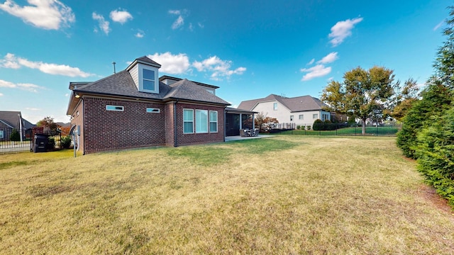 back of house featuring a yard, a fenced backyard, a shingled roof, and brick siding