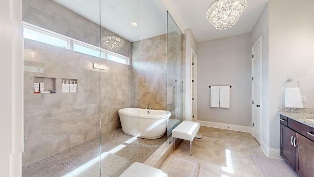 bathroom featuring a freestanding tub, a notable chandelier, vanity, baseboards, and a tile shower