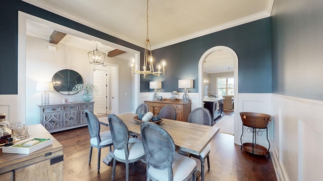 dining space featuring a wainscoted wall, arched walkways, dark wood-type flooring, and ornamental molding