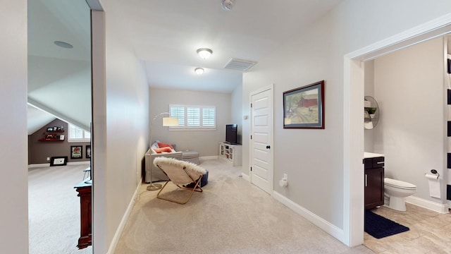 corridor with light carpet, baseboards, visible vents, and lofted ceiling