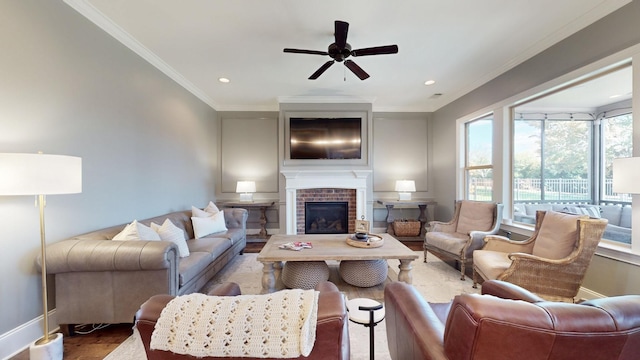 living room with baseboards, ceiling fan, ornamental molding, wood finished floors, and a fireplace