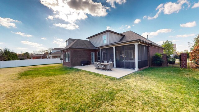 rear view of property featuring a patio area, fence, a sunroom, and a lawn