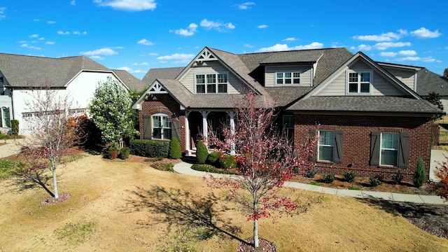 view of front of home featuring a shingled roof, brick siding, and a front lawn