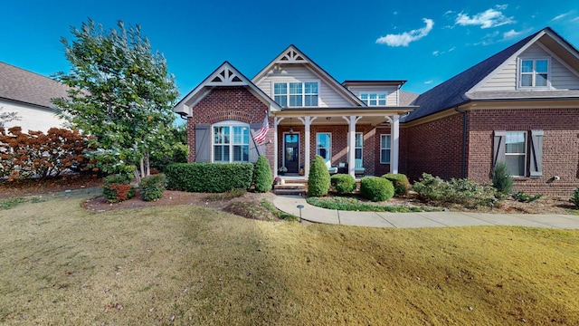 craftsman-style home with a porch, a front lawn, and brick siding