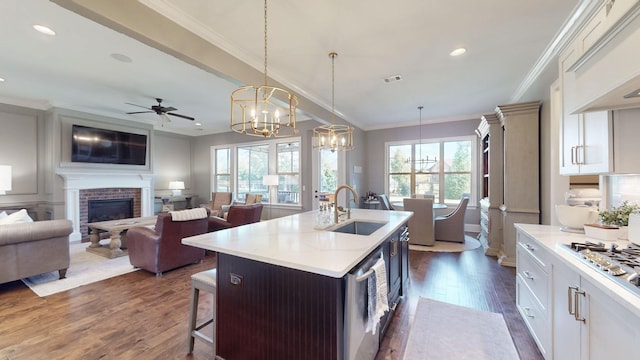 kitchen with visible vents, dark wood-style flooring, light countertops, a brick fireplace, and a sink