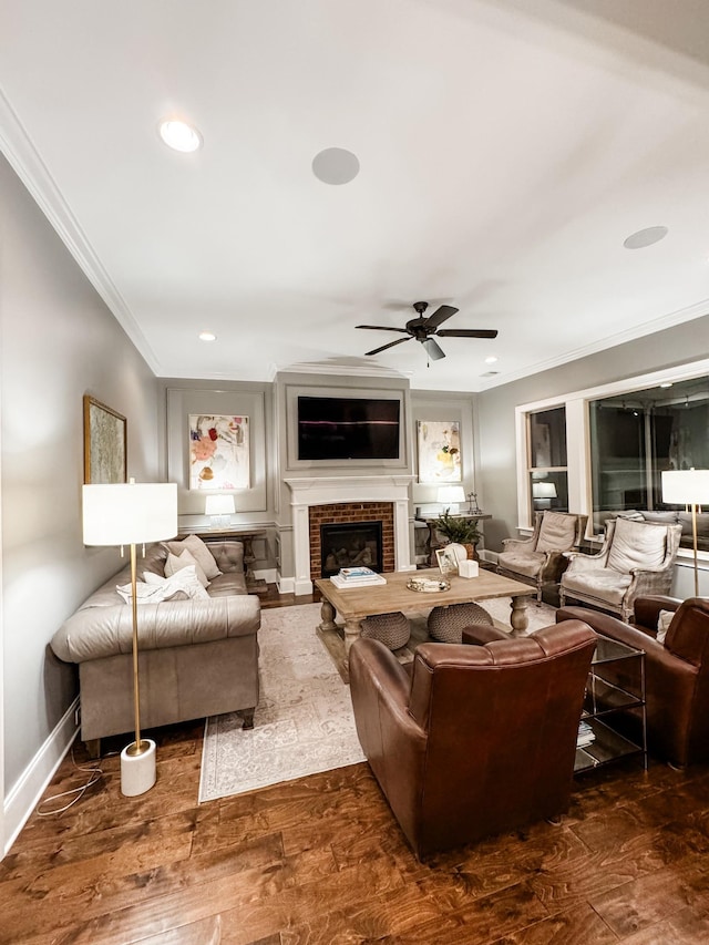 living area with a brick fireplace, baseboards, dark wood finished floors, and crown molding