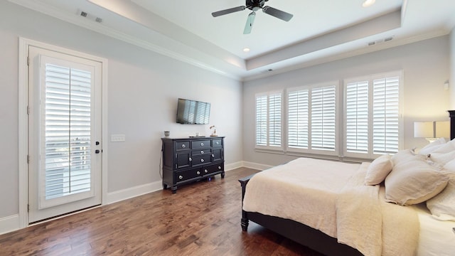 bedroom featuring a raised ceiling, visible vents, baseboards, and wood finished floors