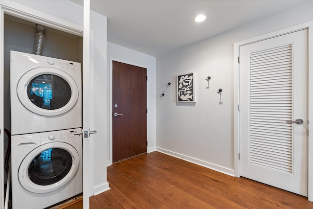 washroom featuring stacked washer / dryer, laundry area, baseboards, and wood finished floors