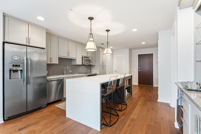 kitchen with a kitchen island, appliances with stainless steel finishes, light countertops, and wood finished floors