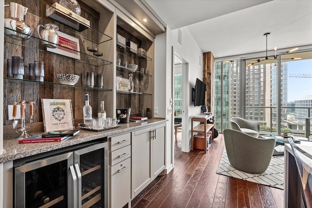 bar featuring beverage cooler, a bar, a wall of windows, and dark wood finished floors