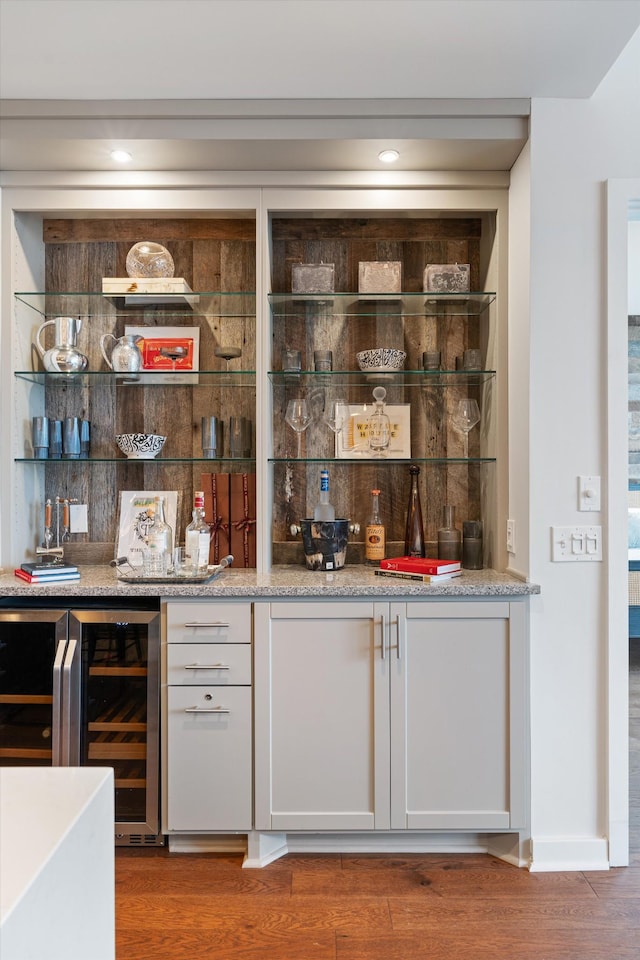 bar with wine cooler, a bar, and wood finished floors