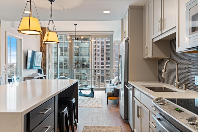 kitchen with stainless steel appliances, gray cabinets, light countertops, decorative backsplash, and wood finished floors