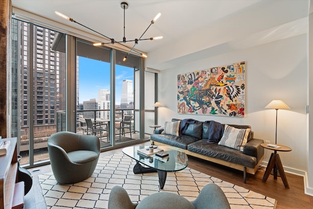 living area featuring a city view, an inviting chandelier, wood finished floors, a wall of windows, and baseboards