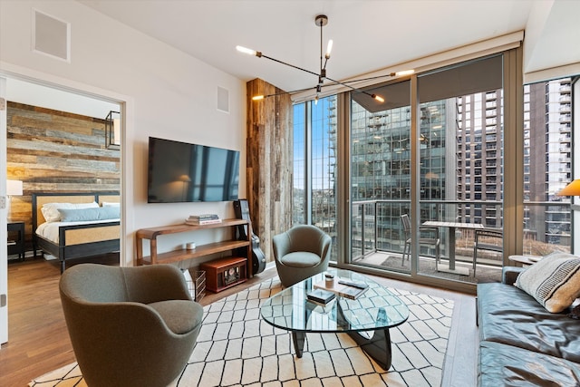 living room with plenty of natural light, expansive windows, a chandelier, and wood finished floors