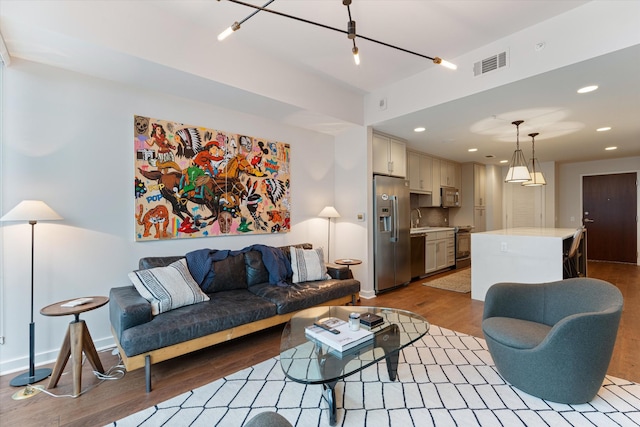 living area with light wood-type flooring, baseboards, visible vents, and recessed lighting